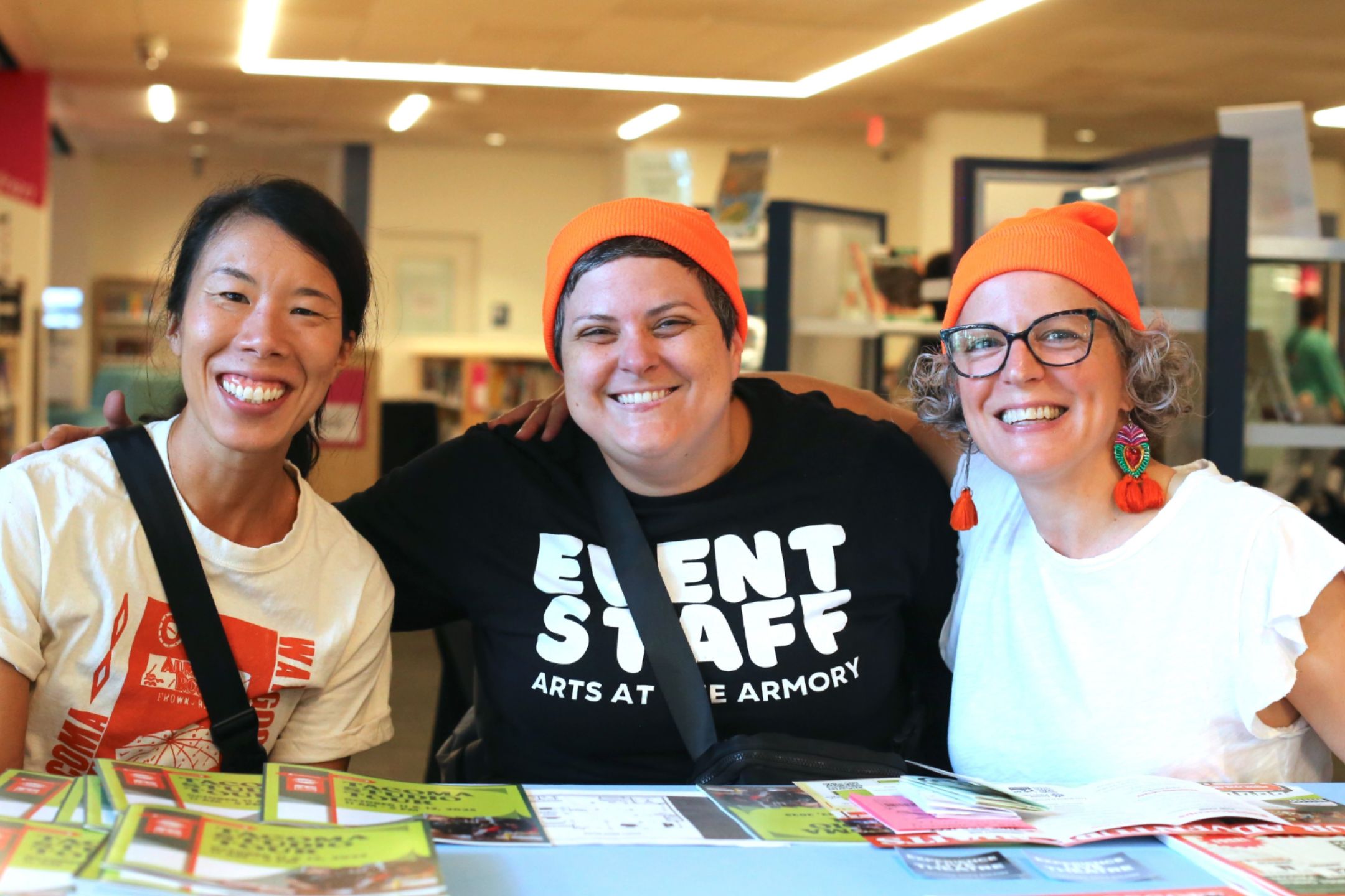 3 Event Support staff smile at visitors during Kaleidoscope, the opening celebration to Tacoma Arts Month in 2025.